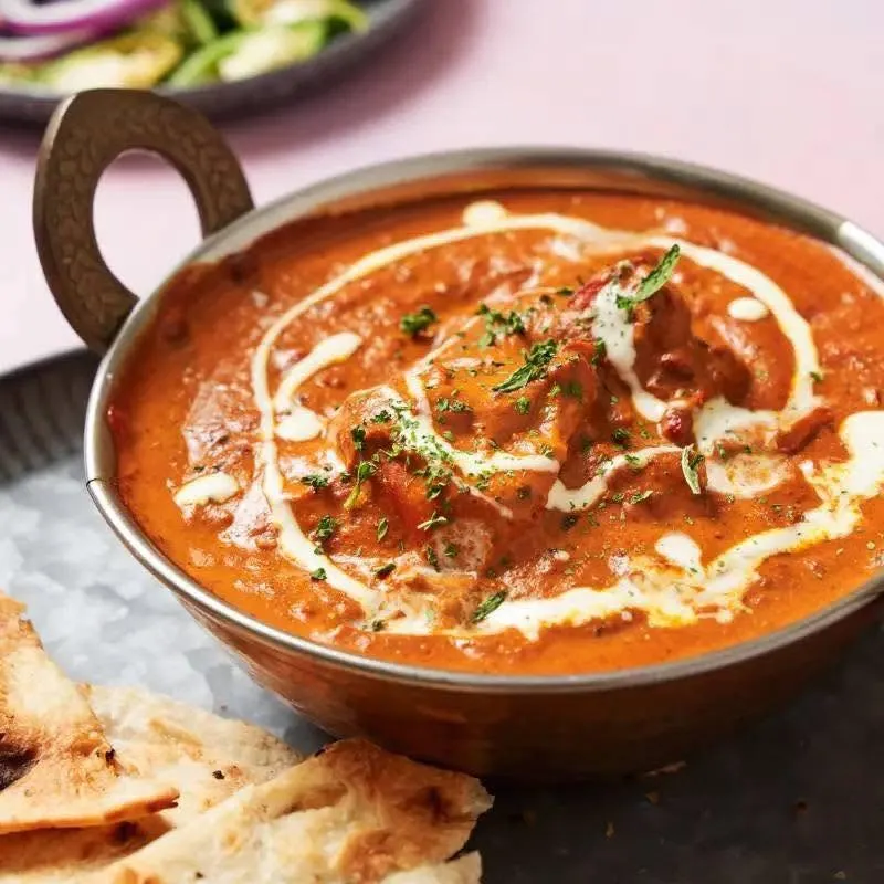 Butter chicken in creamy tomato gravy served with naan at Friendz Dhaba in Brampton, Ontario